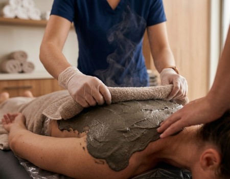 Patient erhält eine Fango-Wärmebehandlung zur Vorbereitung der physiotherapeutischen Therapie in der Physiotherapie Babelsberg